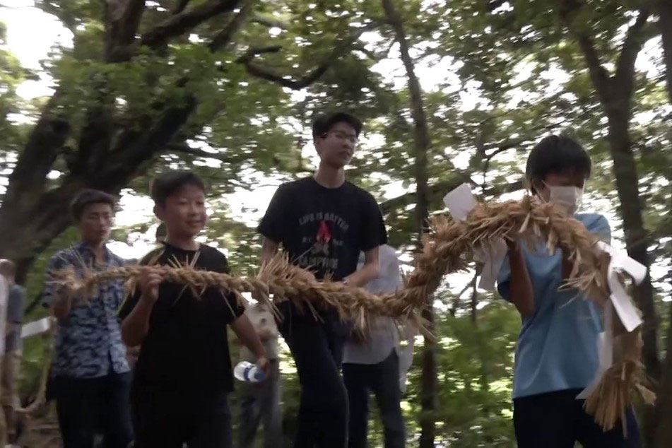 注連縄を持ち社殿を回るく